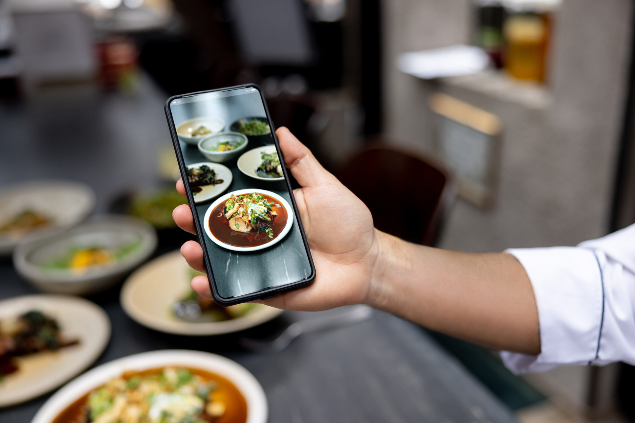 Close-up on a chef taking a picture of a plate at a restaurant to post on social media using a cell phone