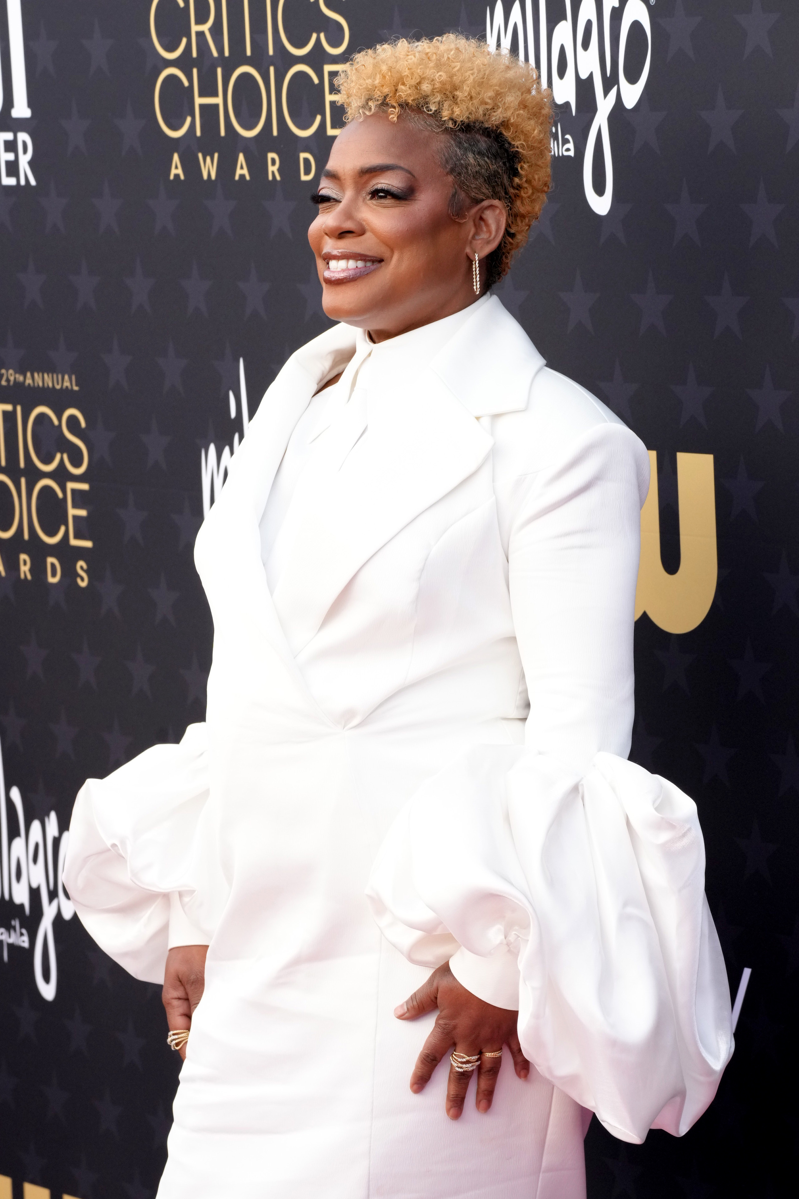 Aunjanue Ellis-Taylor in a suit with large ruffle detail posing in front of the Critics&#x27; Choice Award backdrop