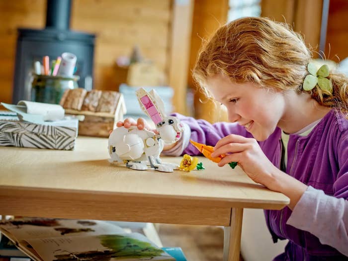 A young girl plays with a LEGO set of a rabbit