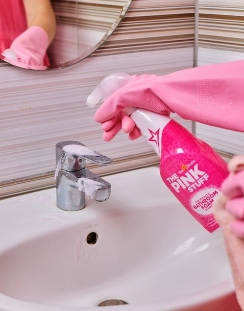 a person using The Pink Stuff to clean a bathroom faucet