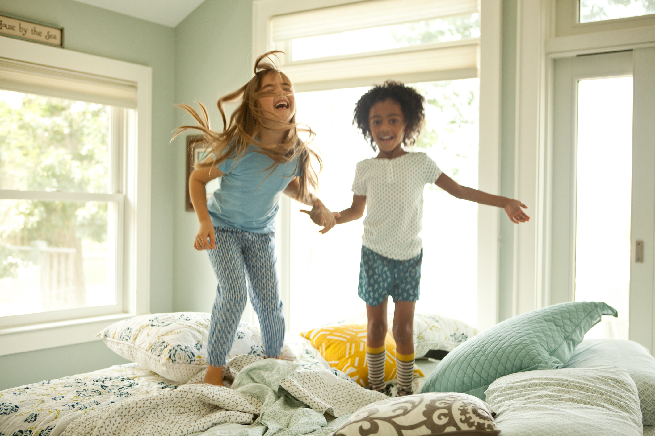two little girls jumping on the bed