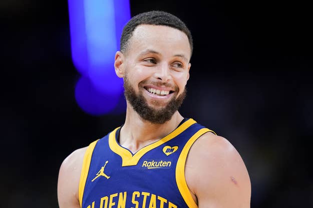 Stephen Curry smiling in his Golden State Warriors basketball uniform during a game