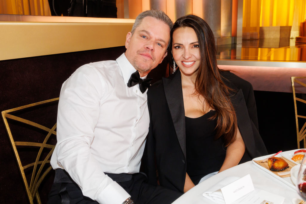 Matt Damon seated with Luciana Barroso, both dressed in formal attire at an event