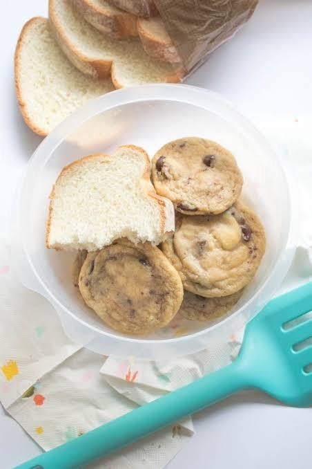 A slice of a bread in a container of cookies