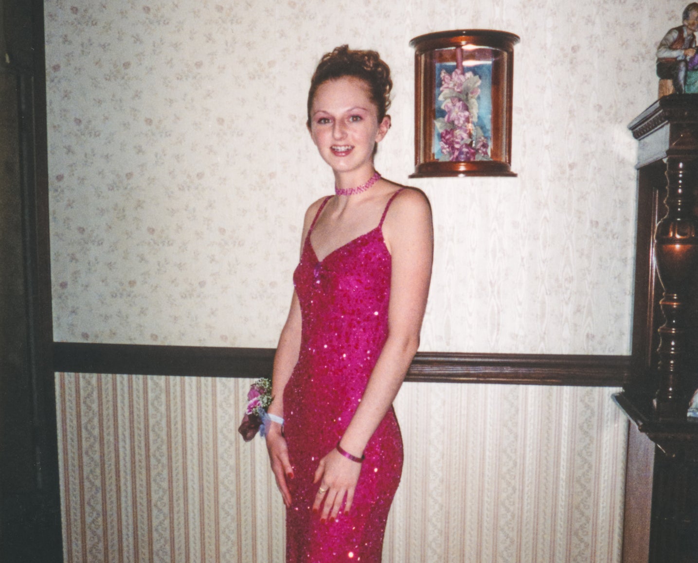 Woman in a sparkly, sleeveless dress with a corsage, standing in a room with vintage decor