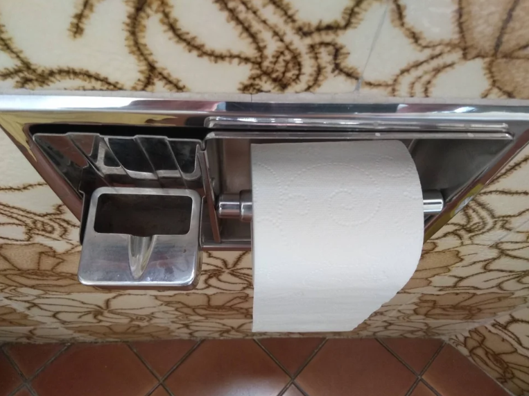 an ashtray next to a roll of toilet paper