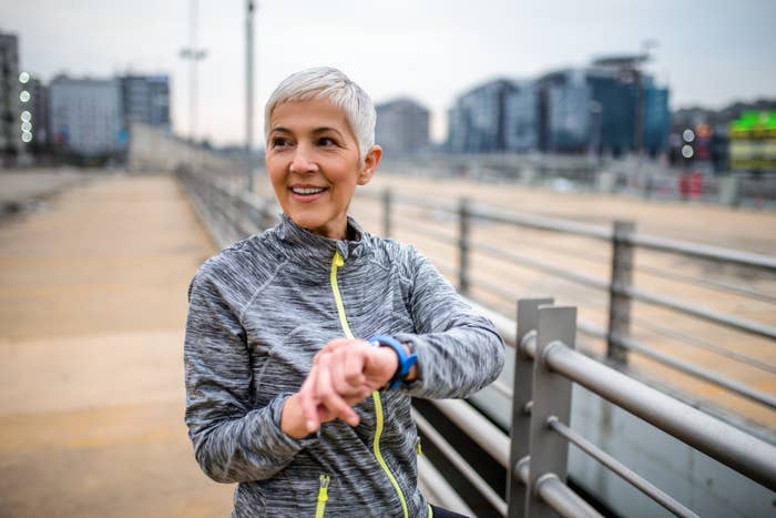 Mature woman with short hair checks watch during outdoor workout