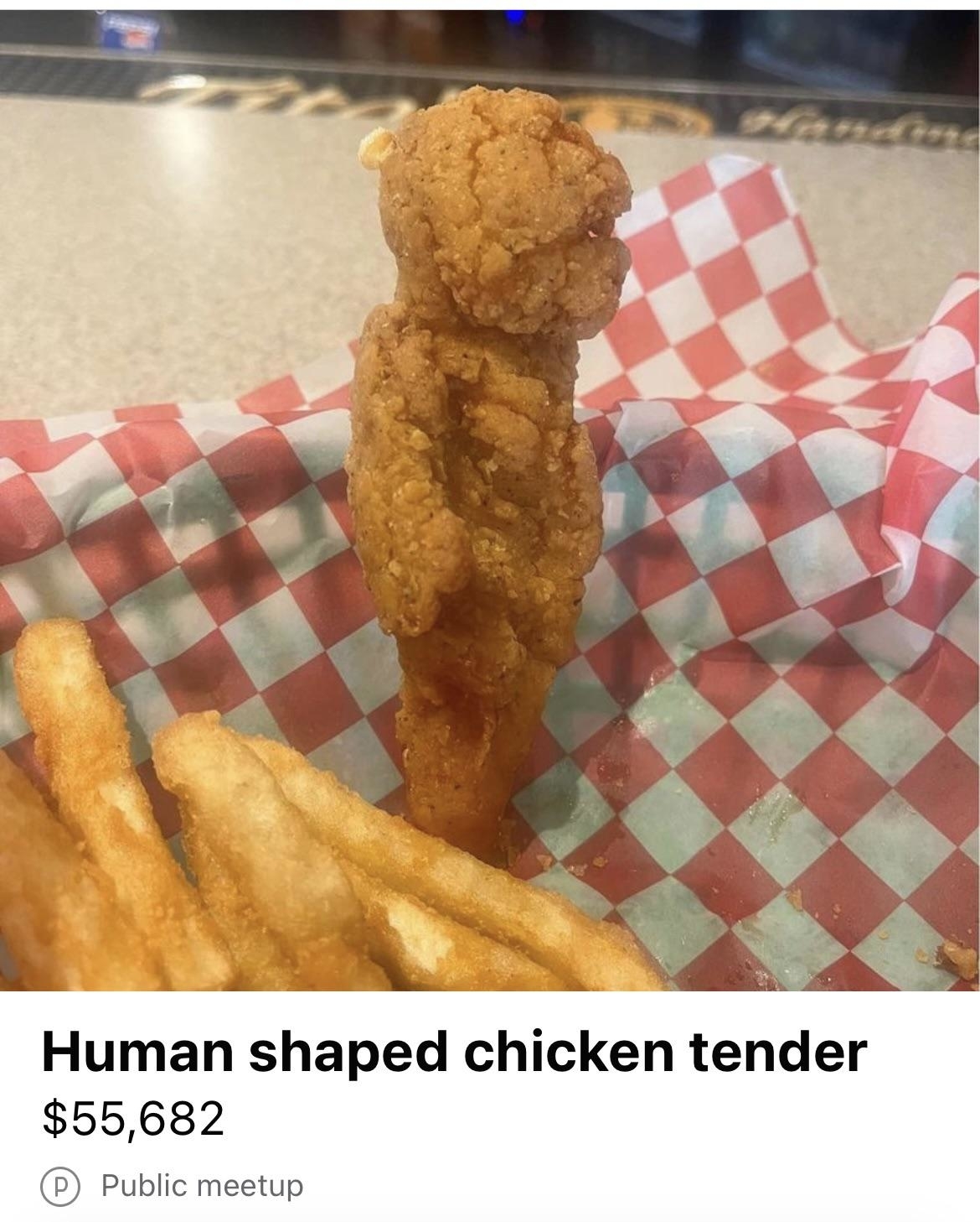 Chicken tender resembling a human figure next to fries on checkered paper, for $55,682
