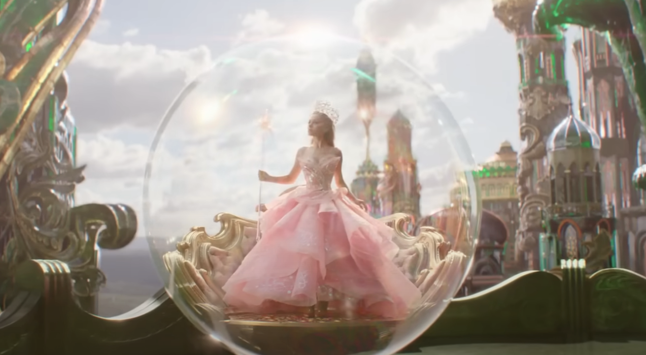 Ariana Grande in a sparkling gown inside a translucent bubble with a whimsical castle backdrop in &quot;Wicked&quot;