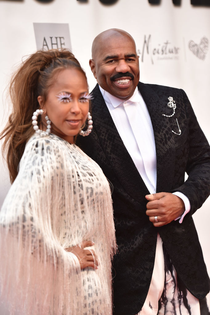 The couple on a red carpet; Marjorie on the left with fringed attire and Steve on the right in a patterned suit