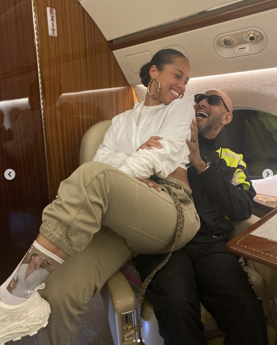 Two people embracing joyfully inside a private jet, one seated on the other&#x27;s lap. Both dressed casually