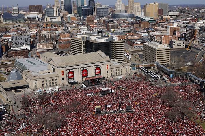 An aerial view of a large crowd gathered outdoors in an urban area for an event