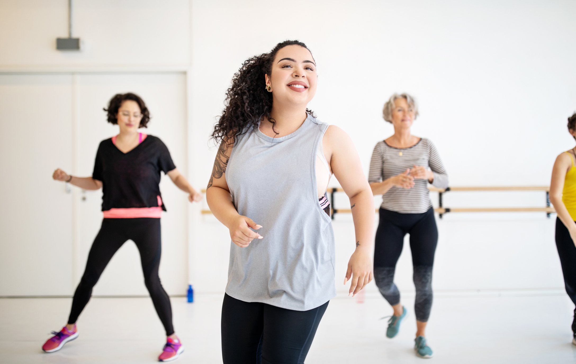 A group of women participating in a dance fitness class, led by an instructor in the foreground