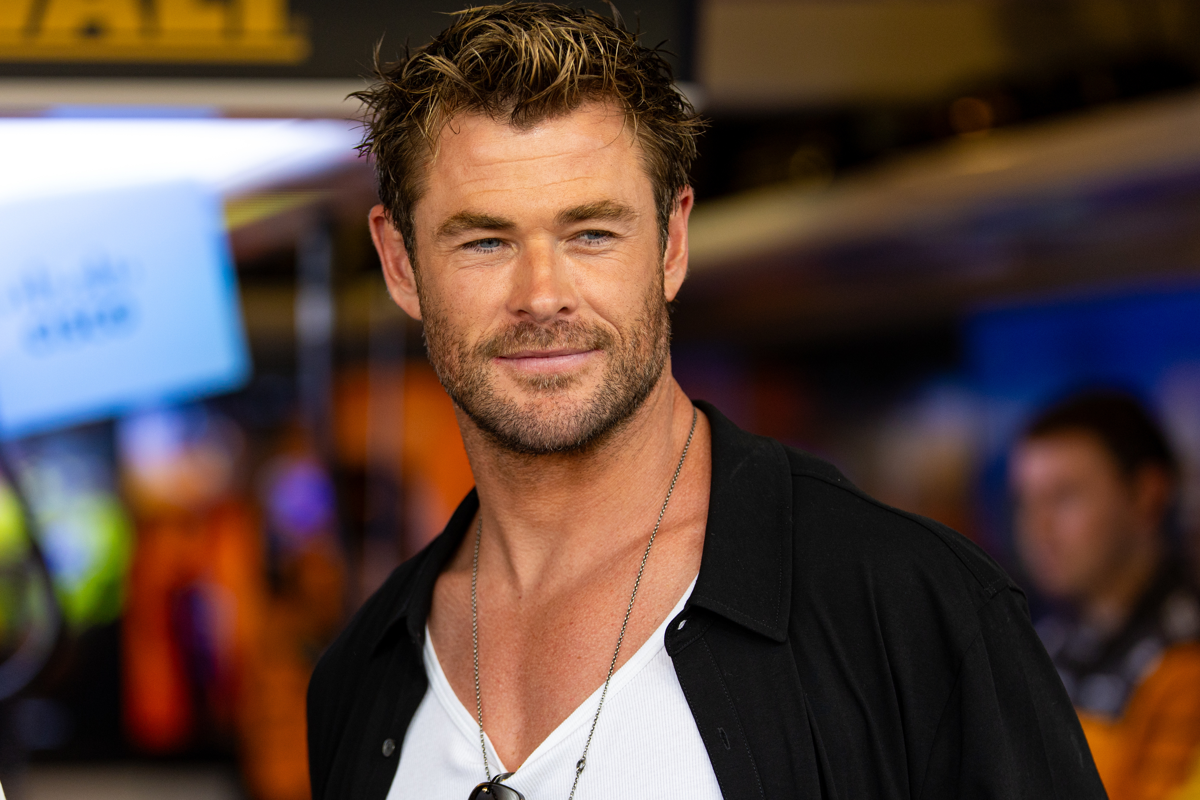 Chris Hemsworth wearing a casual black shirt, smiling at a public event