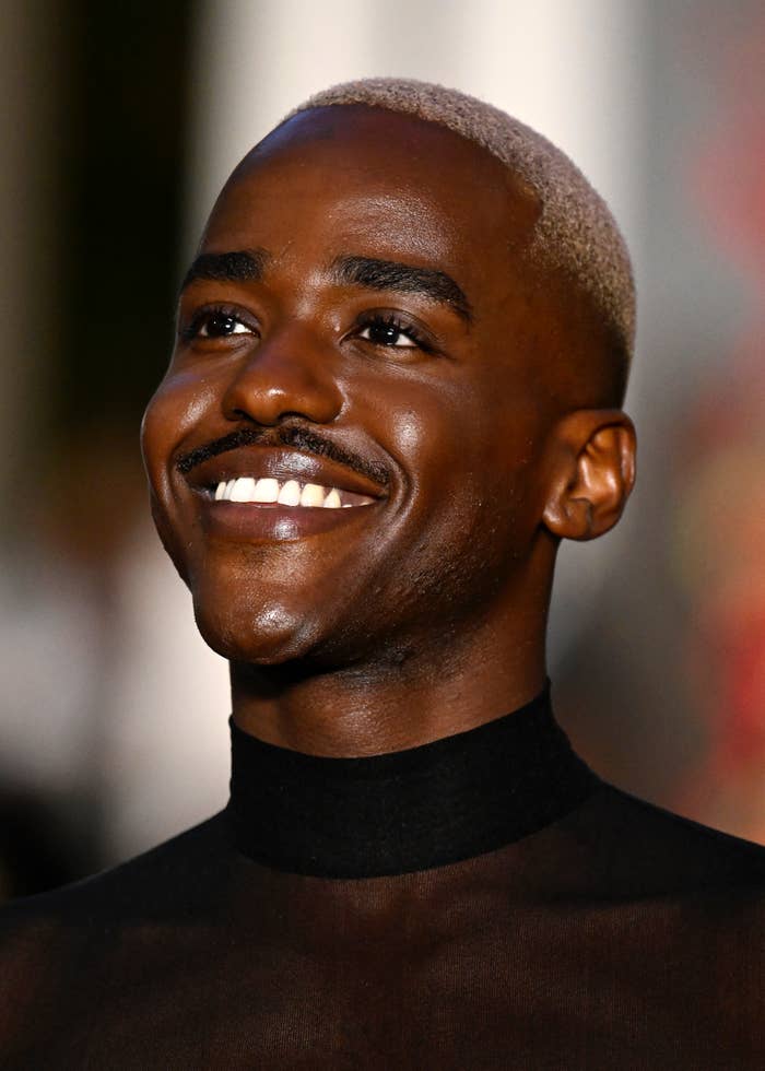 Smiling person in a black turtleneck looking off-camera