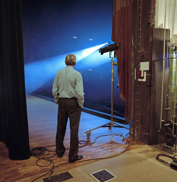 Person on stage looking into the audience with stage lights on