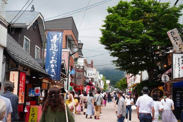 人々が散策する賑やかな商店街、看板や提灯が並ぶ。