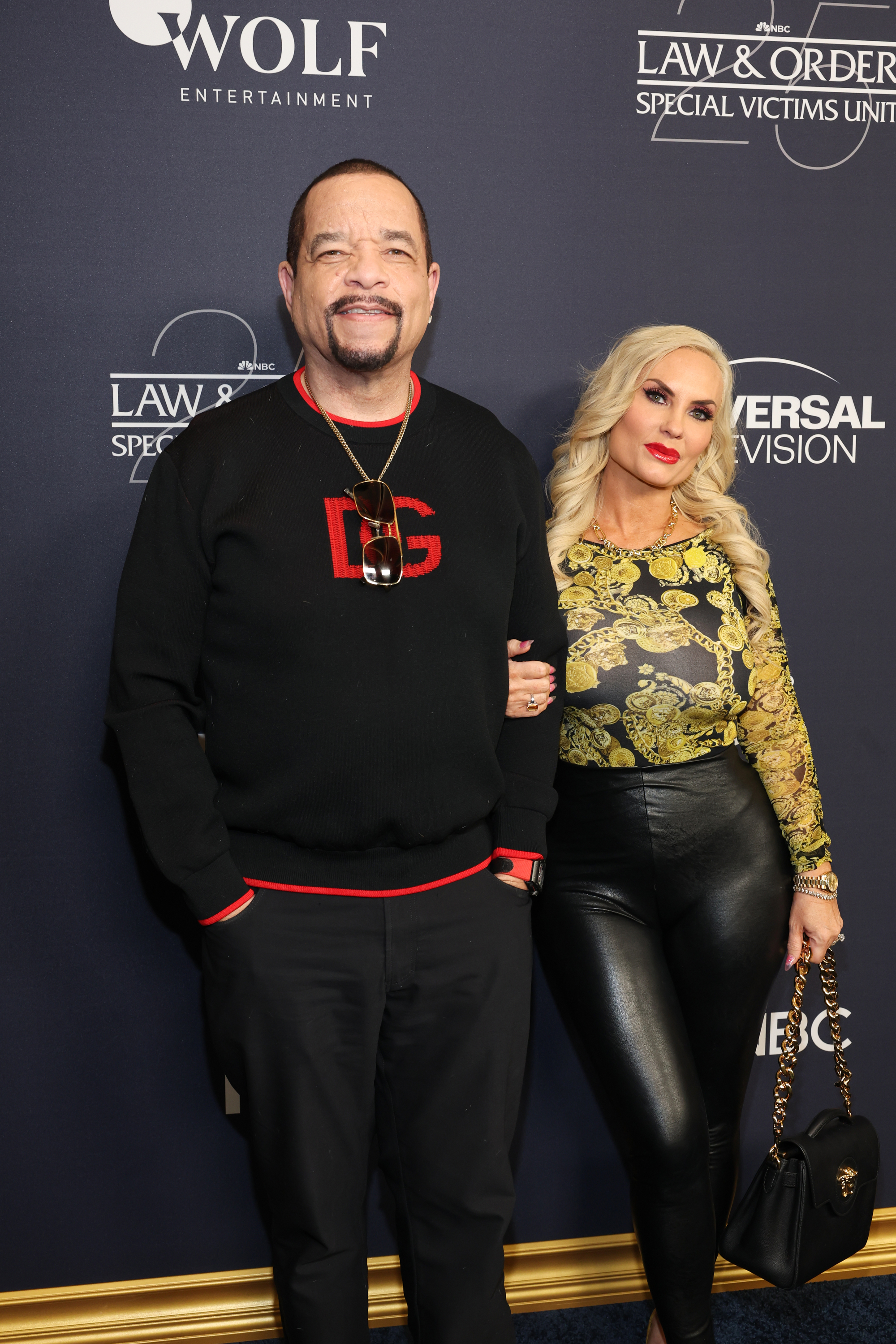 Ice-T and Coco Austin posing together; he&#x27;s in a black and red sweater, she&#x27;s in a gold patterned top and black pants