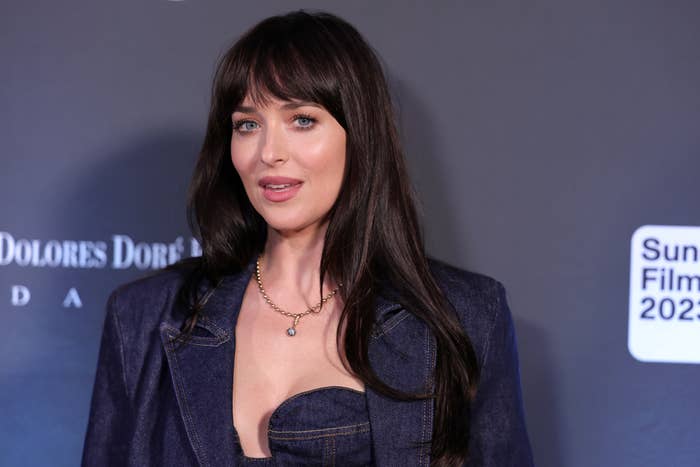 Dakota Johnson stands on the red carpet wearing a stylish denim suit with a necklace