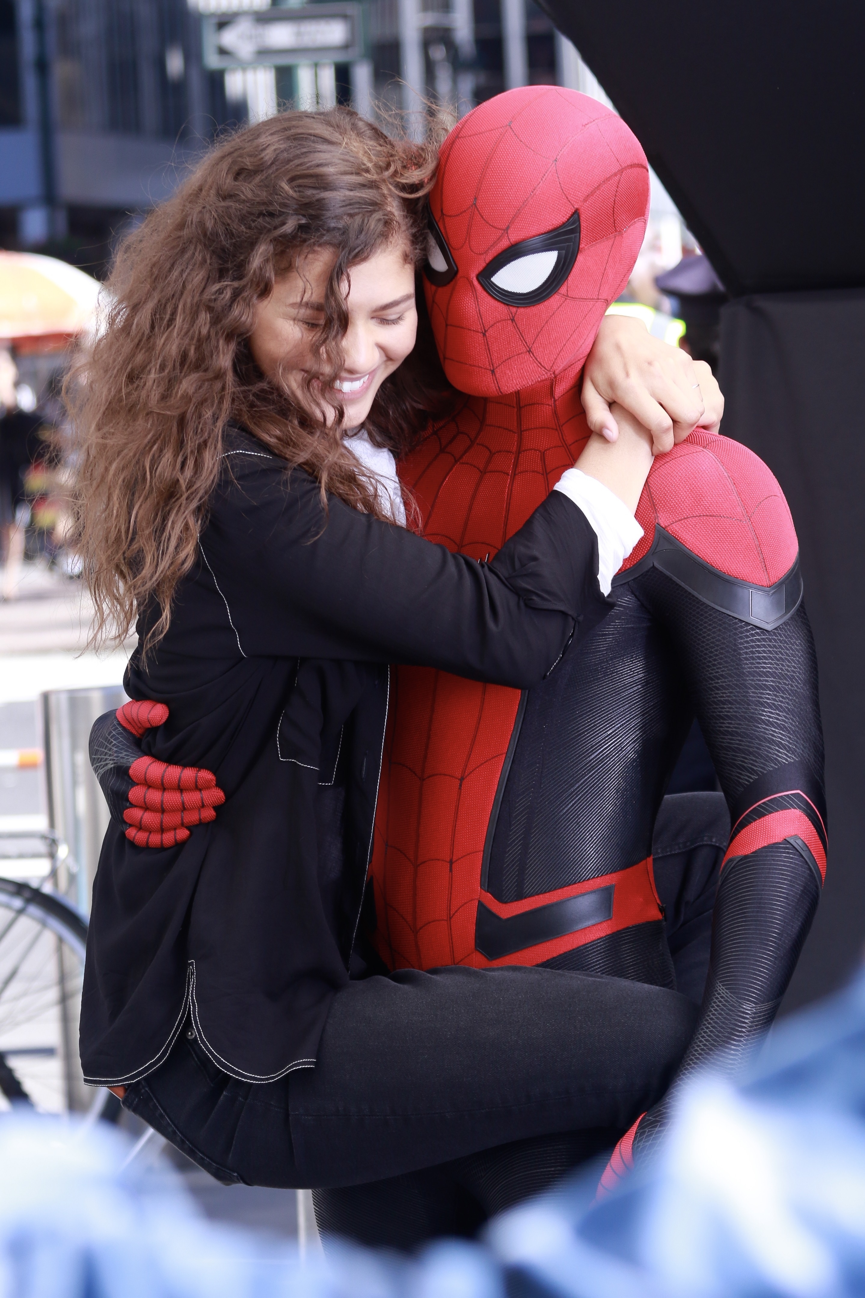 Zendaya smiling and hugging Tom in a Spider-Man costume