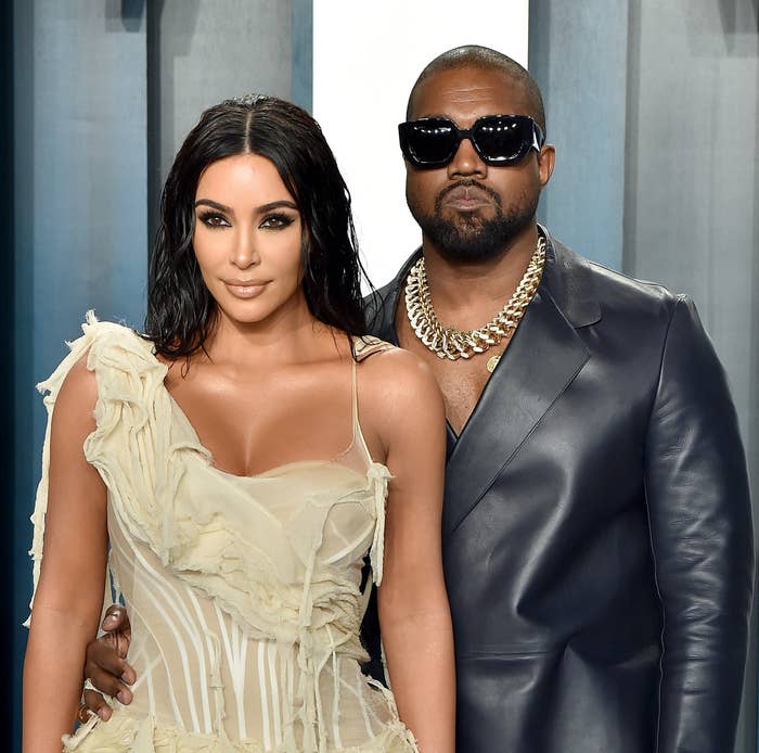 Kim Kardashian in a ruffled dress and Kanye West/Ye in a leather jacket, standing together