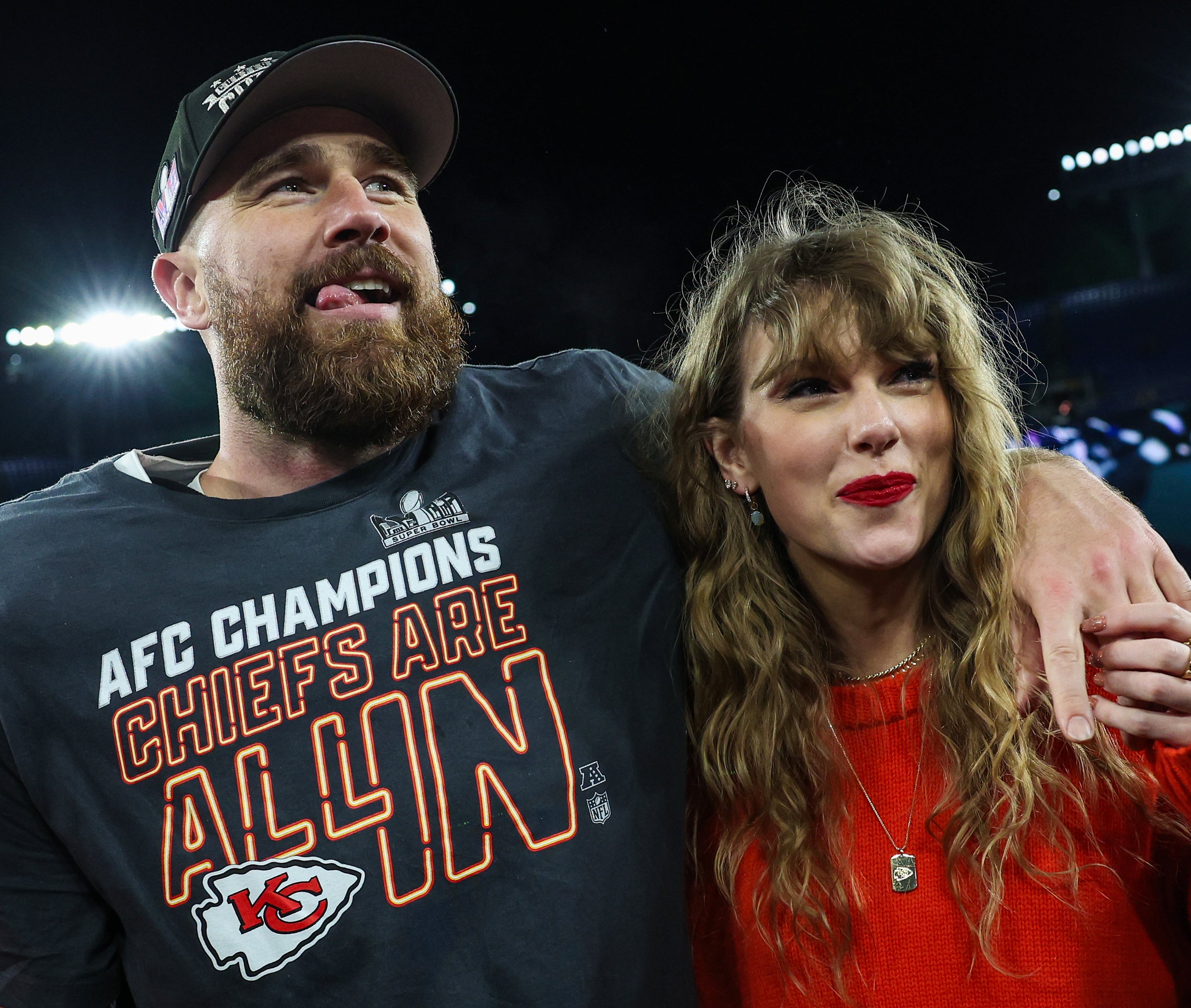 Man in AFC Champions shirt and woman in orange top smiling on football field
