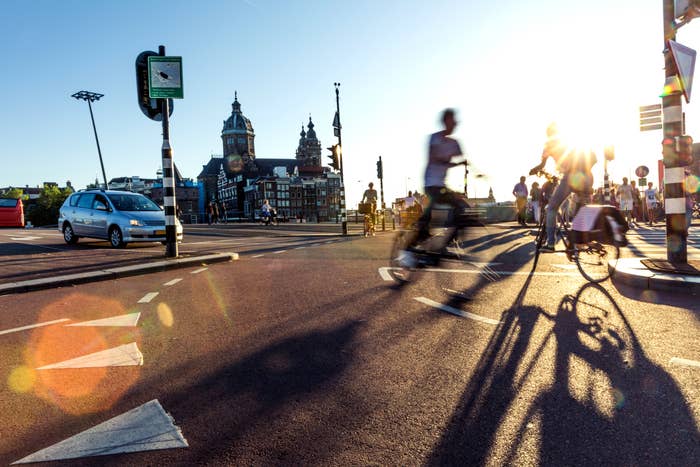 Blurred cyclists and pedestrians crossing busy city intersection