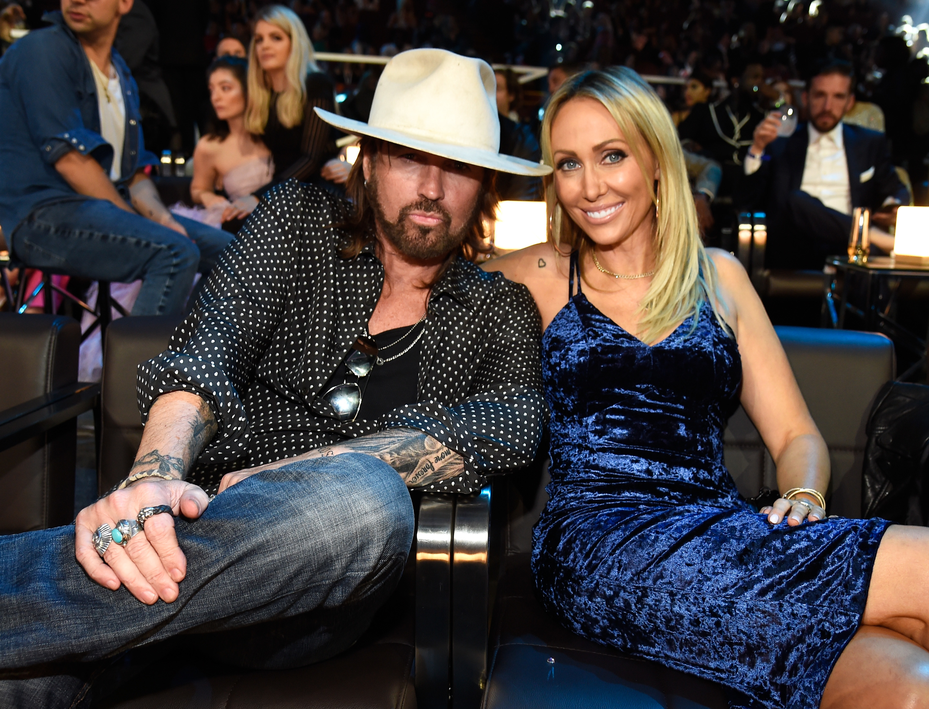 Billy Ray and Tish seated side by side at an event, dressed in smart casual attire