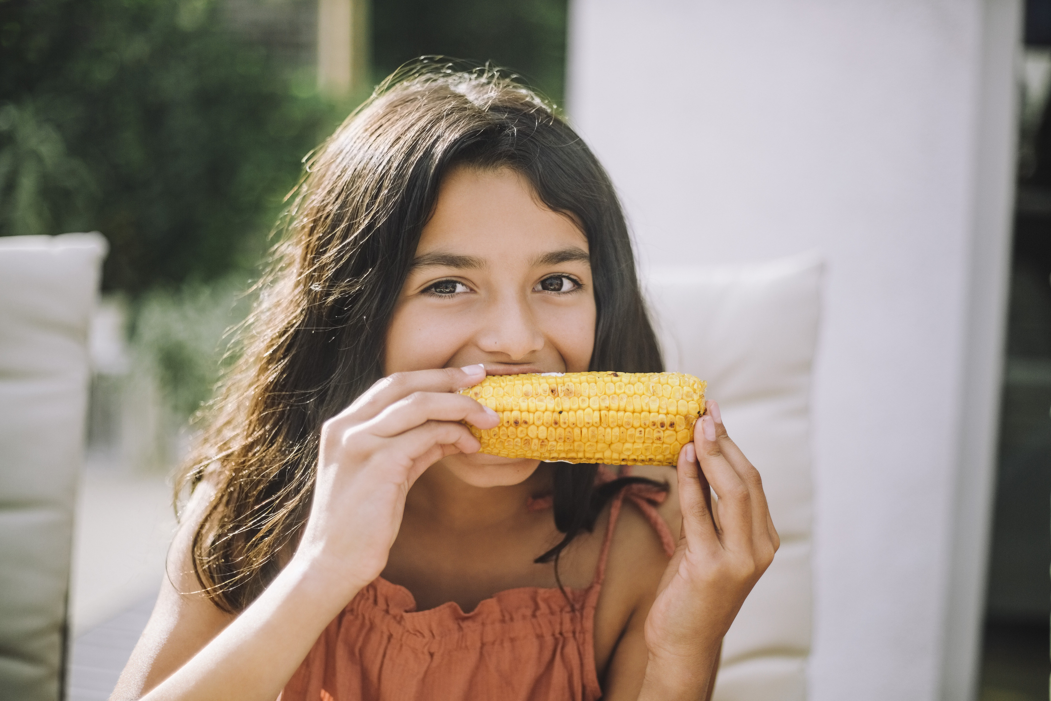 A young girl eating corn on the cob outdoors