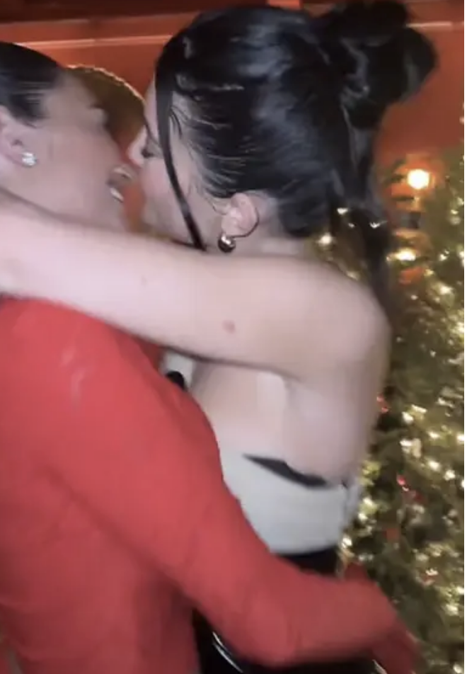 Two people hugging, Stassie in a red blazer, Kylie in a backless dress, near a tree
