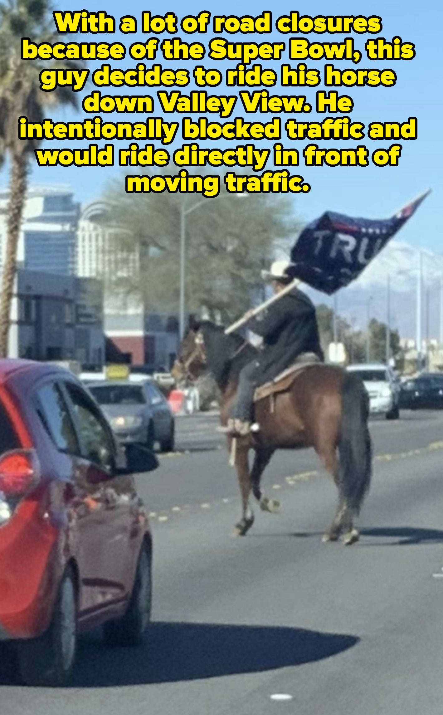 a man on a horse blocking traffic and waving a Trump flag