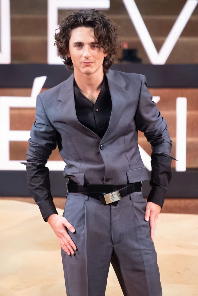 Timothée standing on a stage, wearing a tailored suit