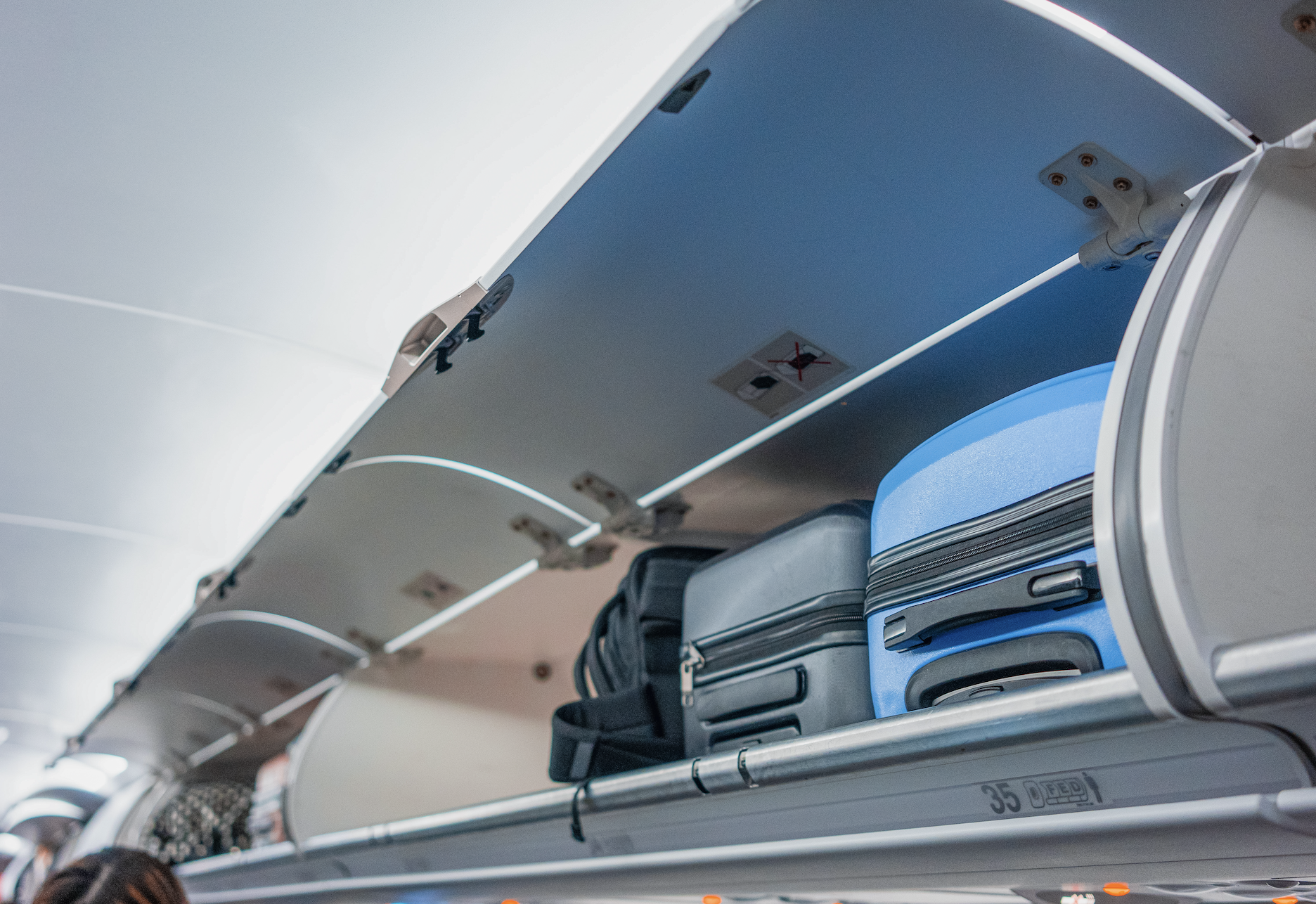 Overhead compartment on an airplane with luggage stored inside