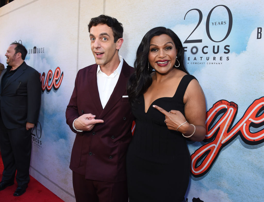 BJ and Mindy on a red carpet, both smiling and gesturing towards the camera