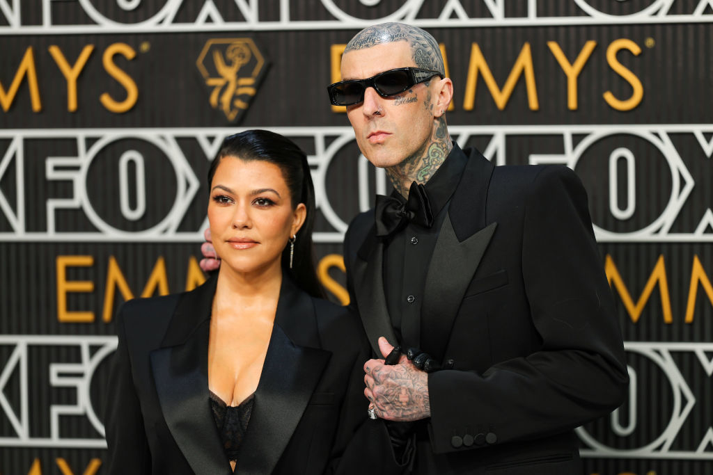 Kourtney Kardashian and Travis Barker posing together in formal attire at an event