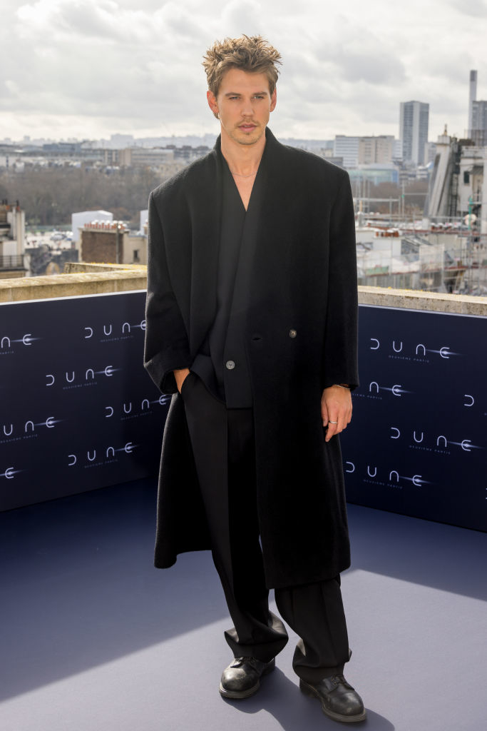 Austin in a stylish coat with cityscape backdrop, posing at a &quot;Dune&quot; event