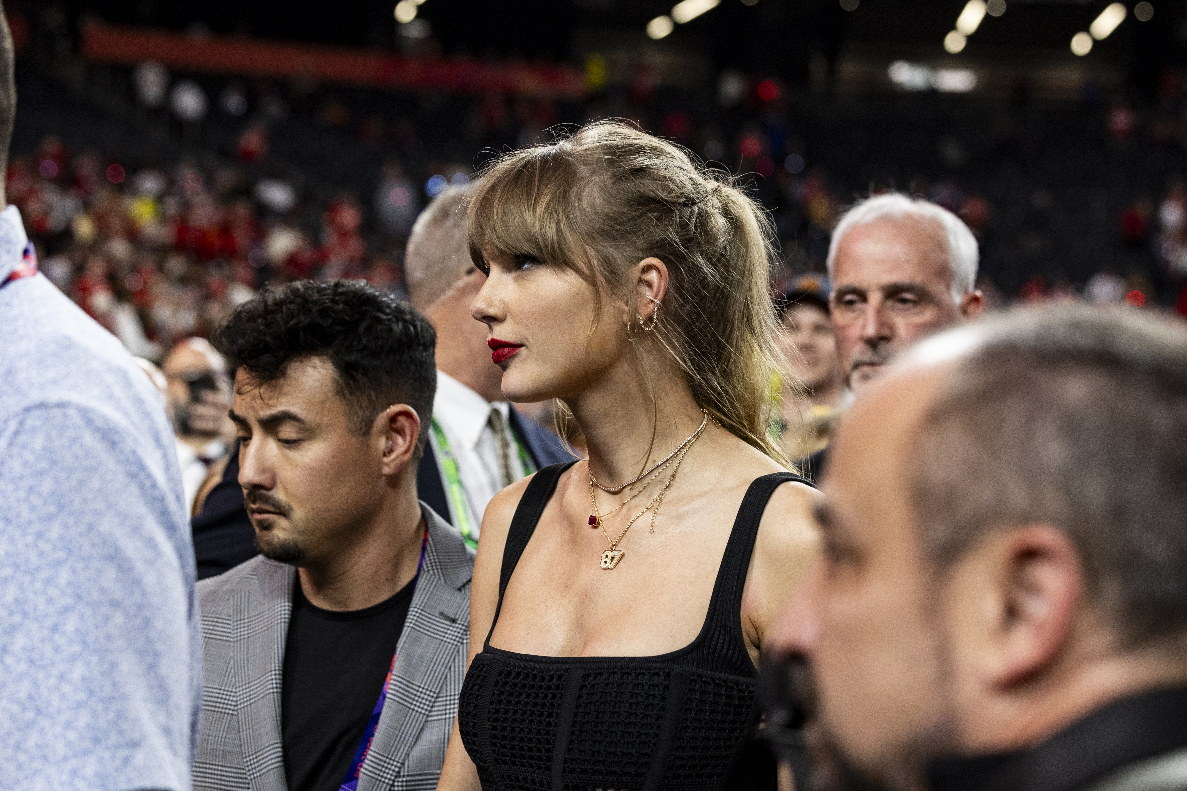 Taylor in a black outfit in a crowd, turning her head to the side