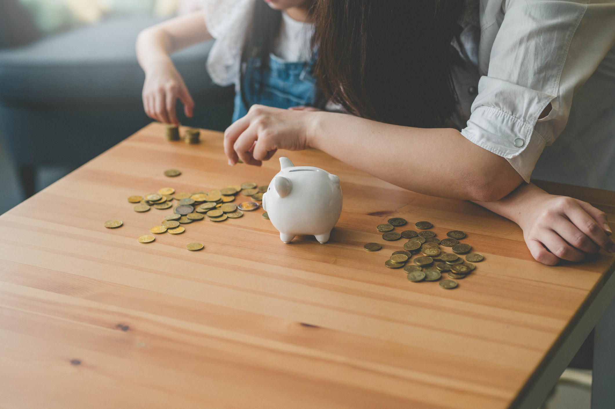 Adult and child counting coins next to a piggy bank, implying financial education