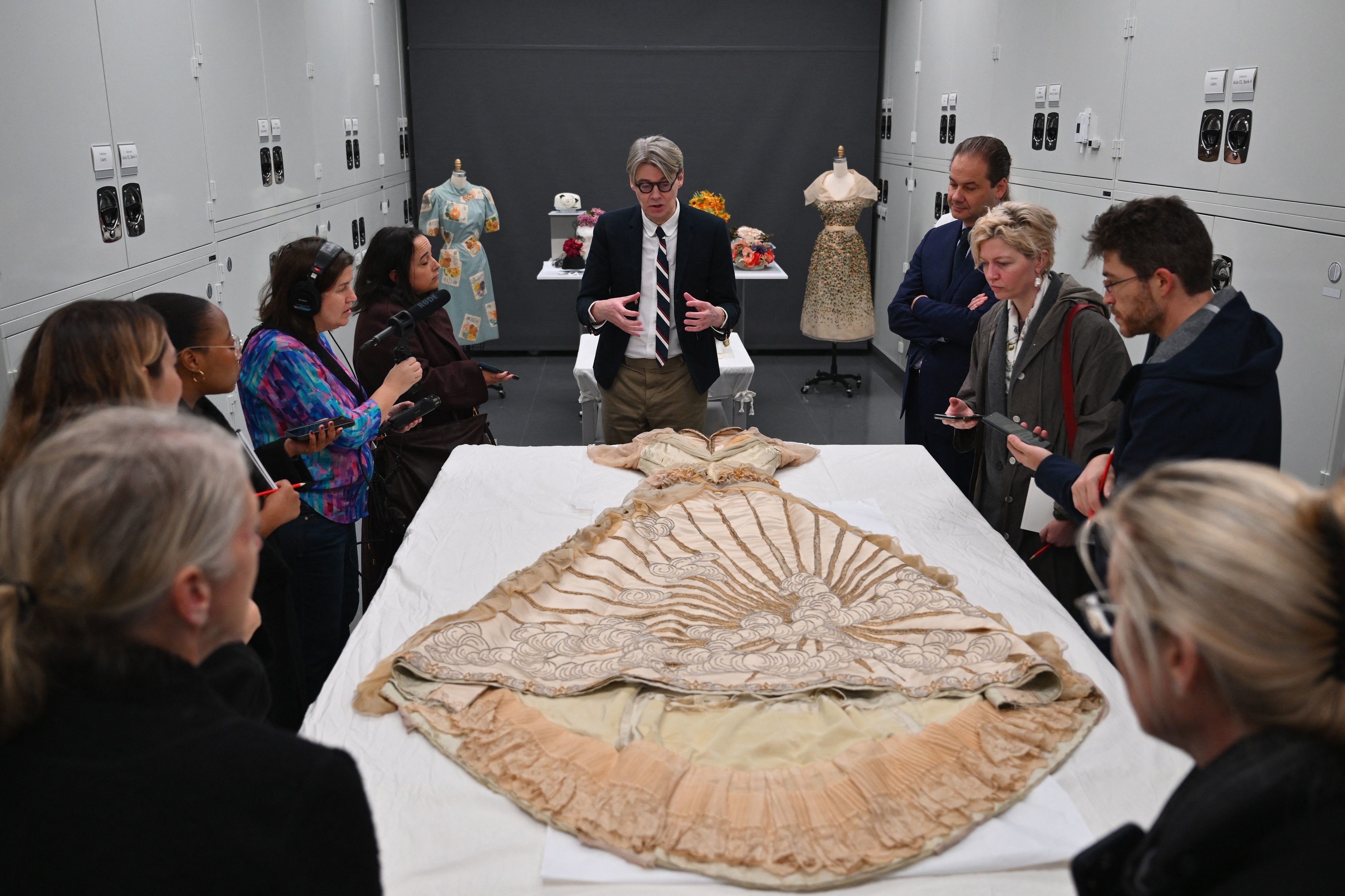 Un grupo de personas observa una prenda antigua extendida en una mesa mientras un experto explica