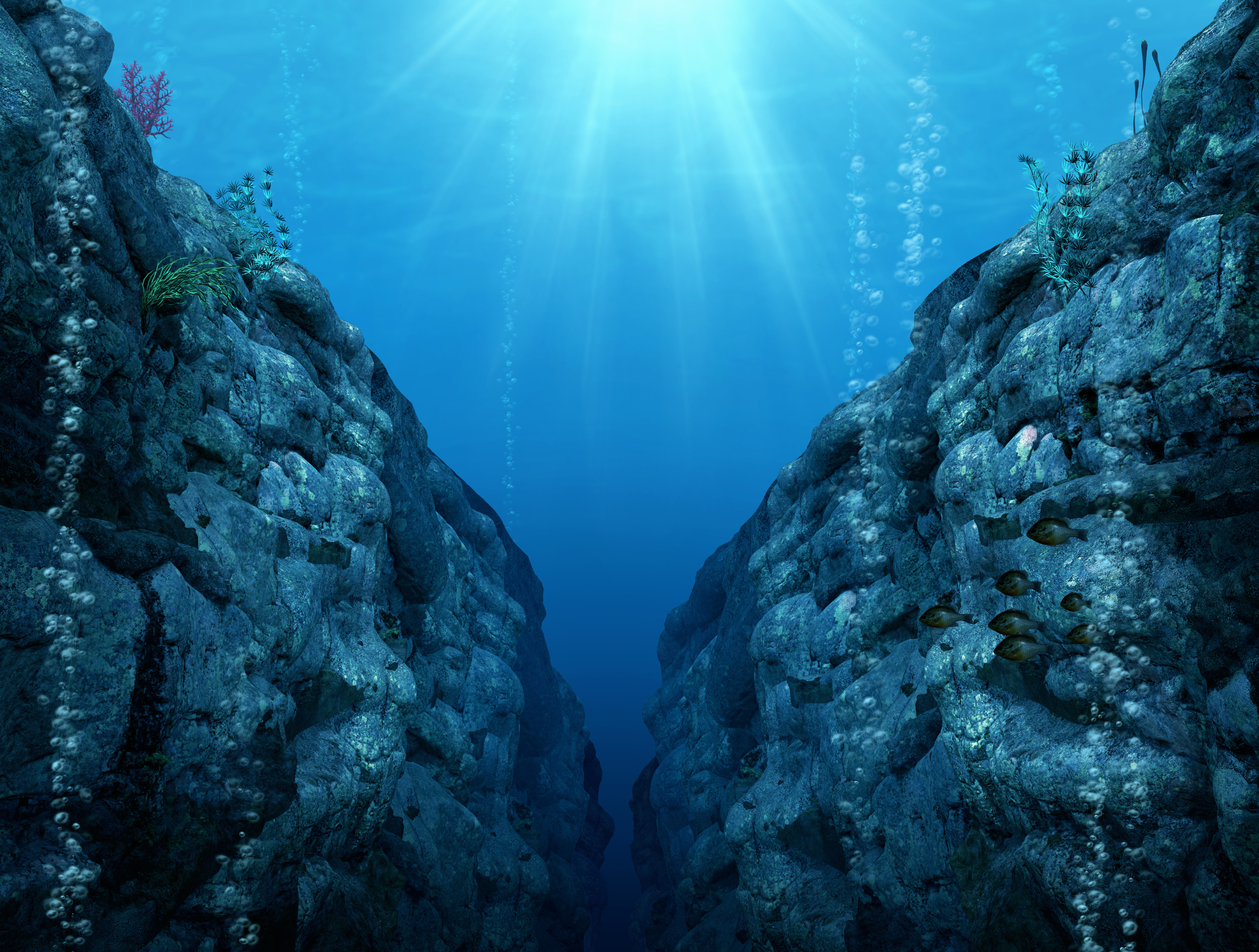 Underwater scene with sun rays shining between two rocky cliffs and small fish visible