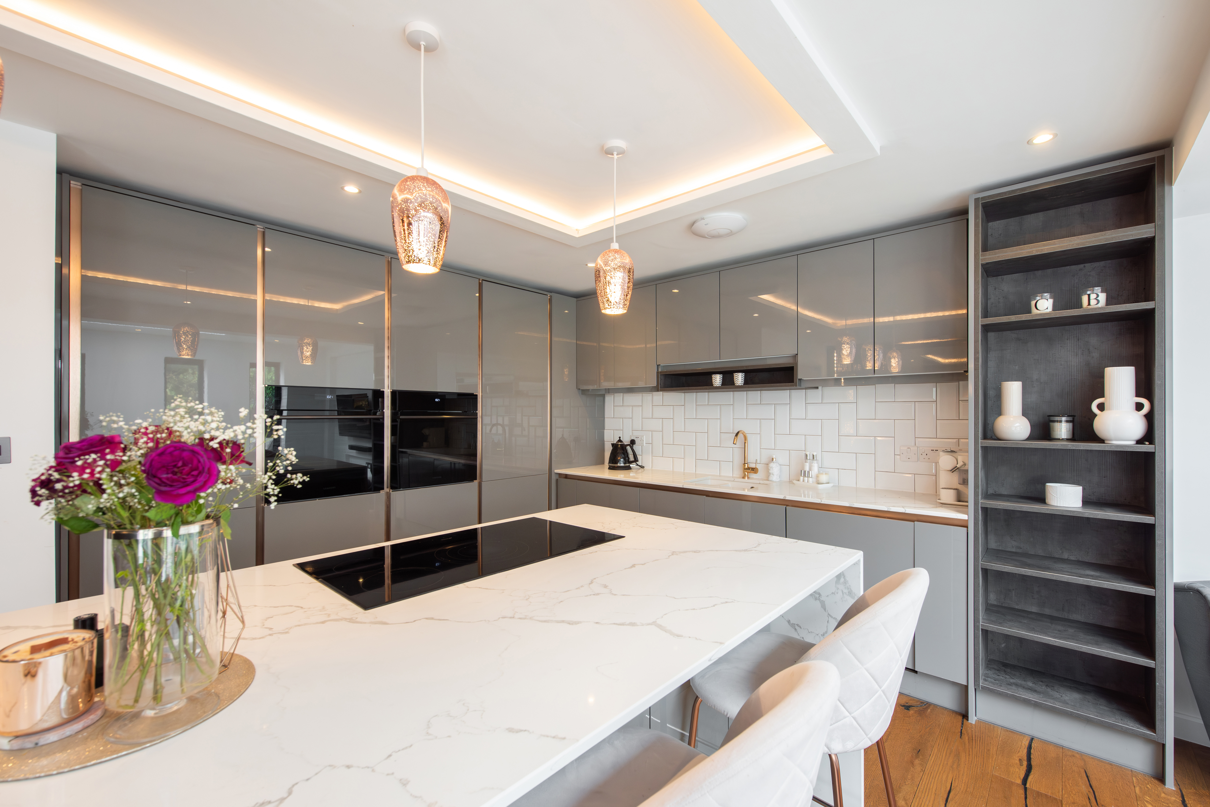 Modern kitchen with marble countertops, built-in appliances, and pendant lights