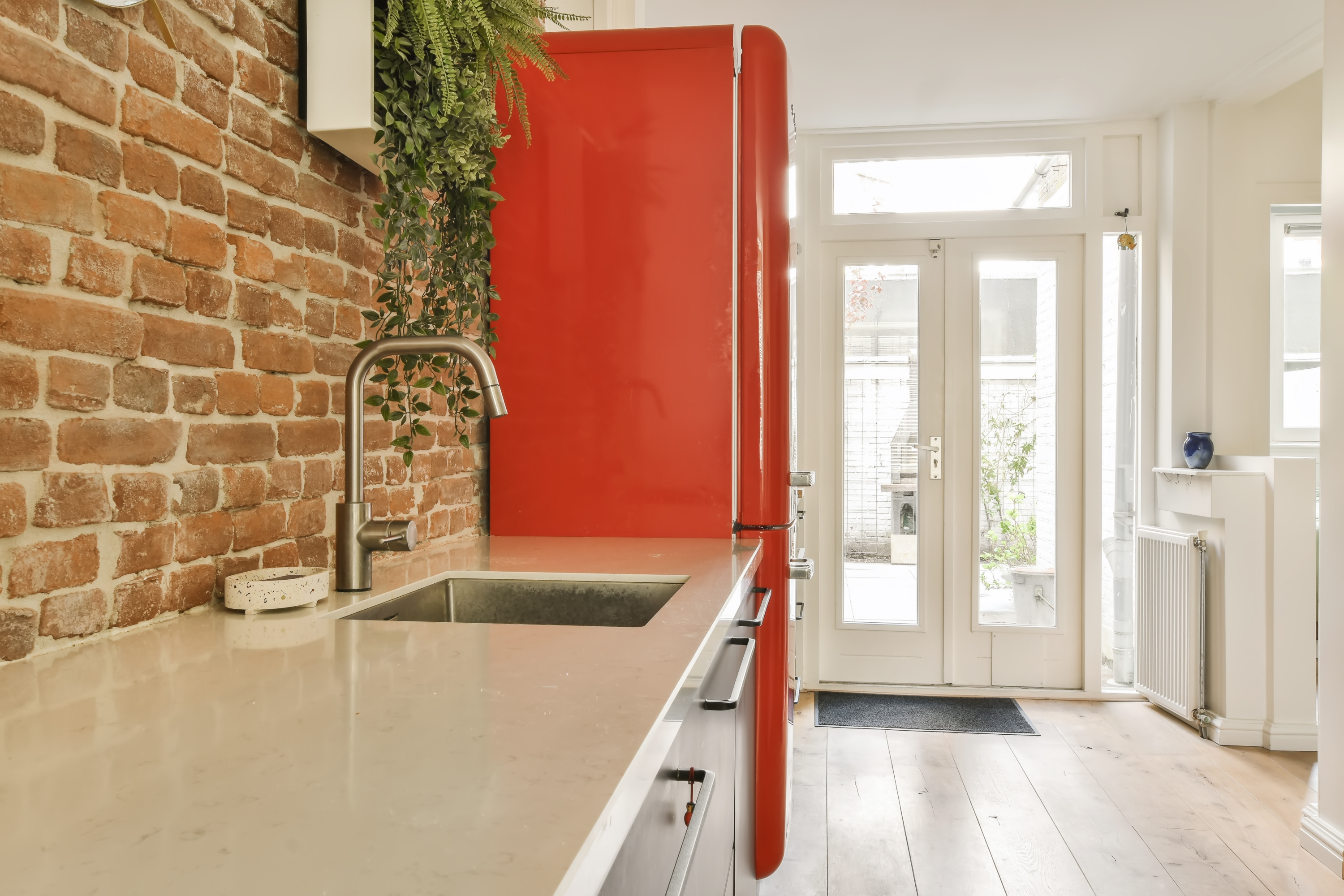 Modern kitchen with a red retro-style refrigerator and exposed brick wall