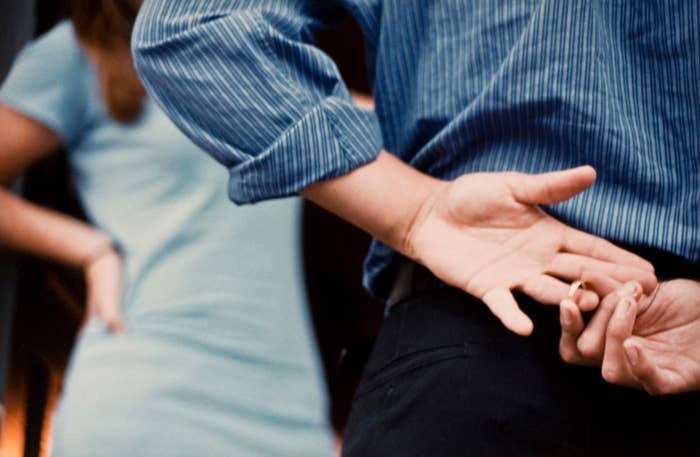 Person secretly taking off their ring behind back while standing near another individual