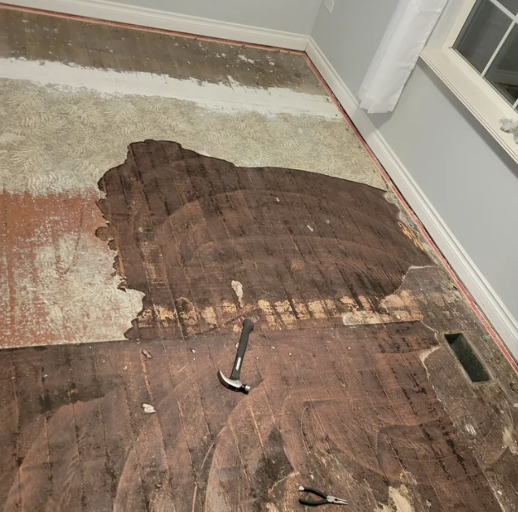 Floor being renovated with some planks removed, revealing old flooring underneath