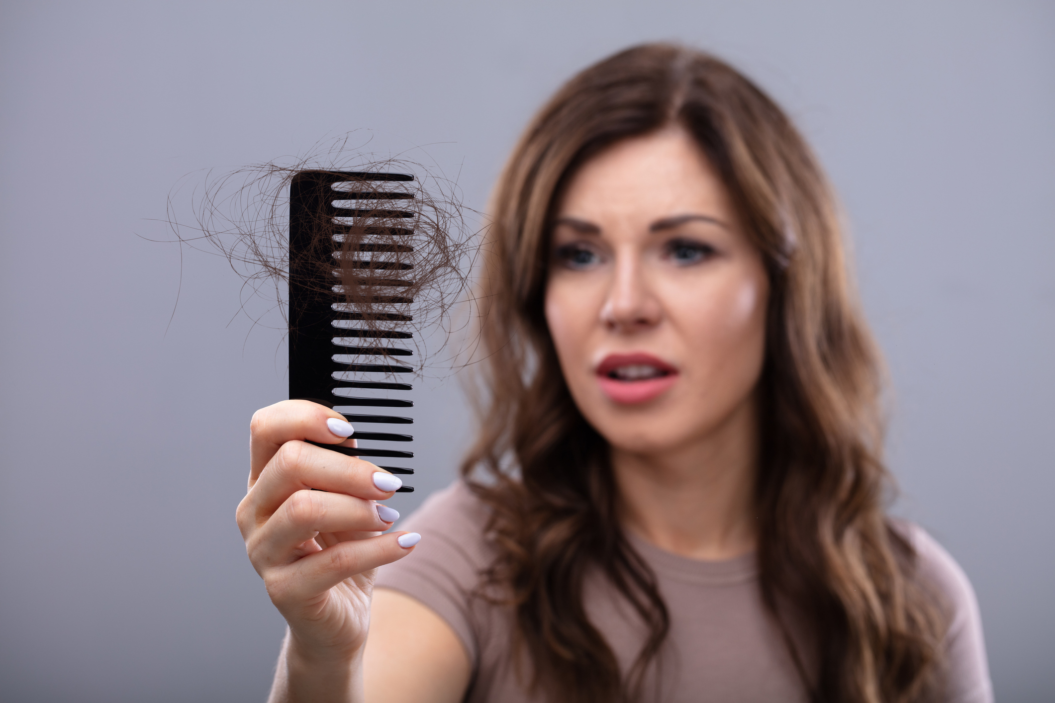 Woman looking worried at a comb with hair in it