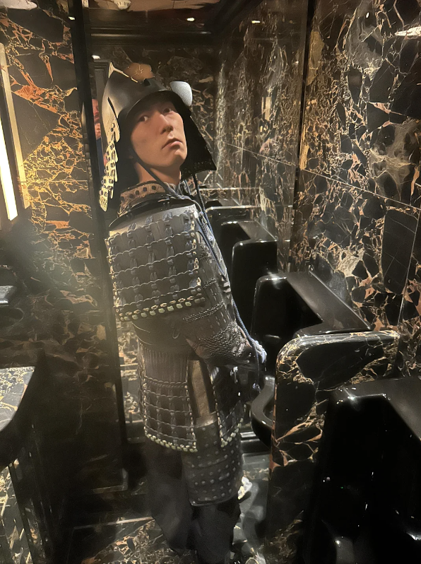 Person in a knight costume posing inside an elevator with dark marble walls