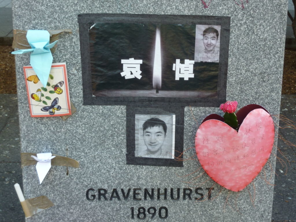 Gravestone with photos and heart-shaped tribute, adorned with ribbons and a floral card