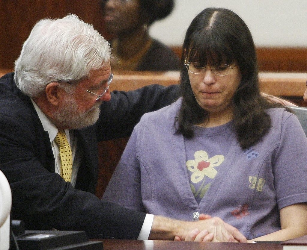 A man comforting Andrea, both sitting in a courtroom