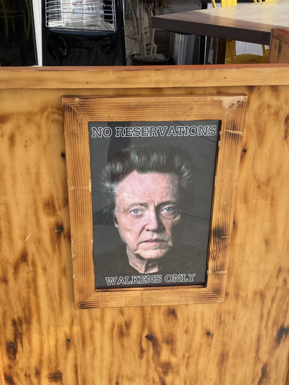 Sign on a restaurant stating "NO RESERVATIONS - WALKENS ONLY" with a portrait of Christopher Walken