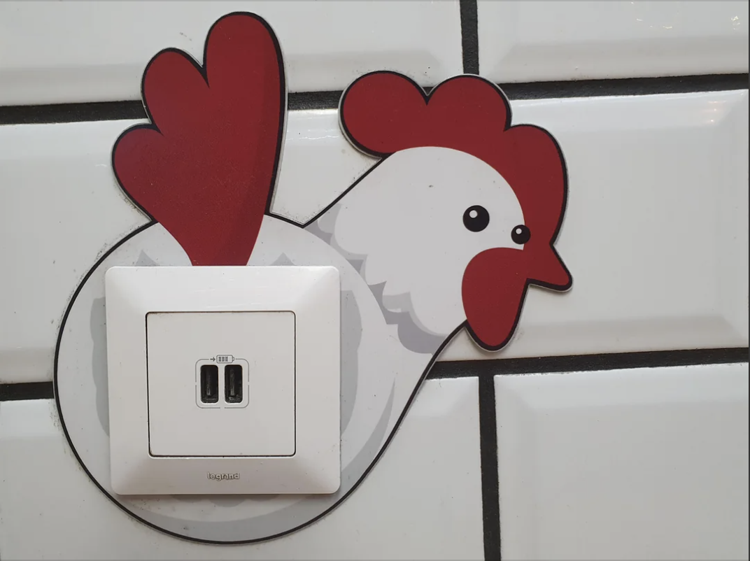 Chicken-shaped cover framing a light switch on a tiled wall